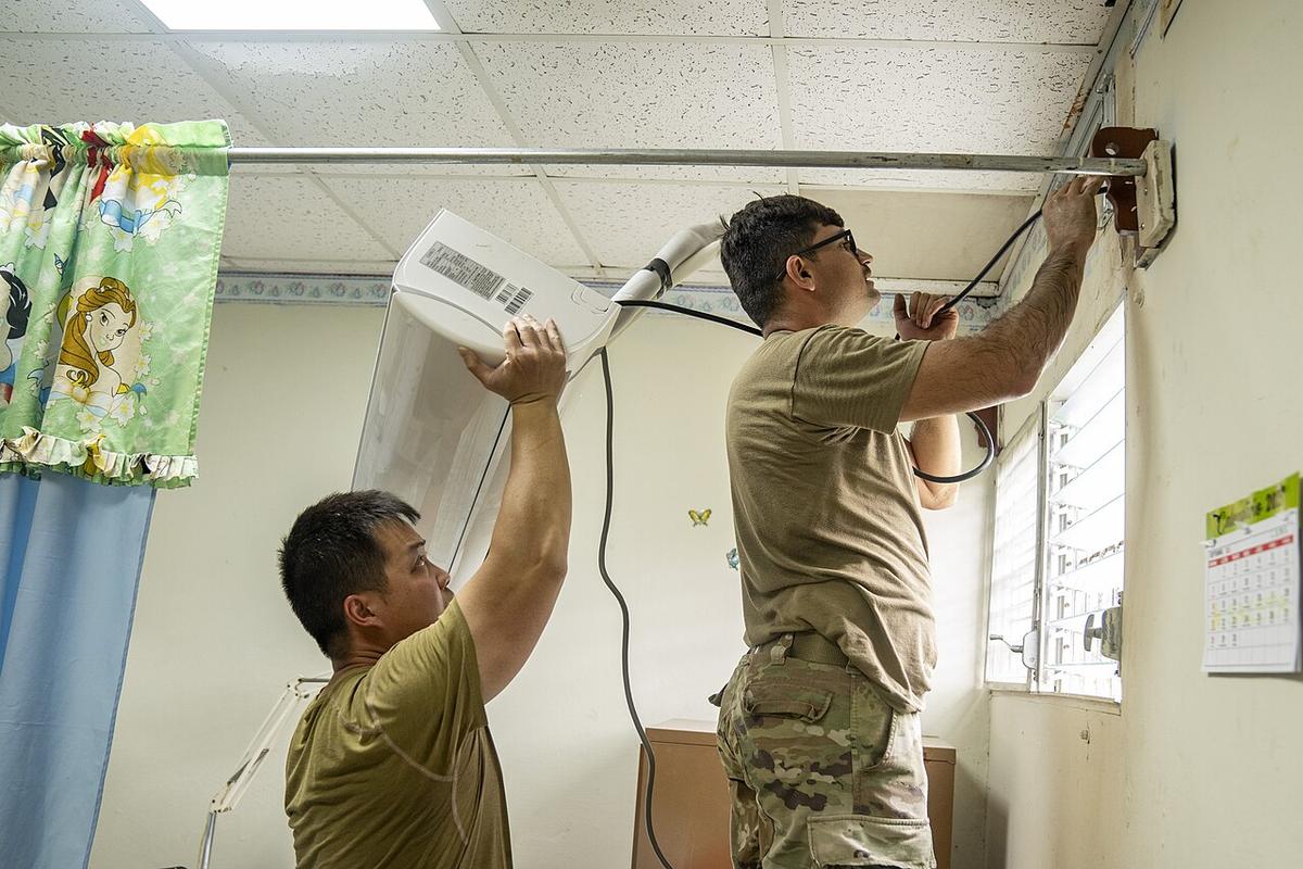 Technicians installing a split system air conditioner
